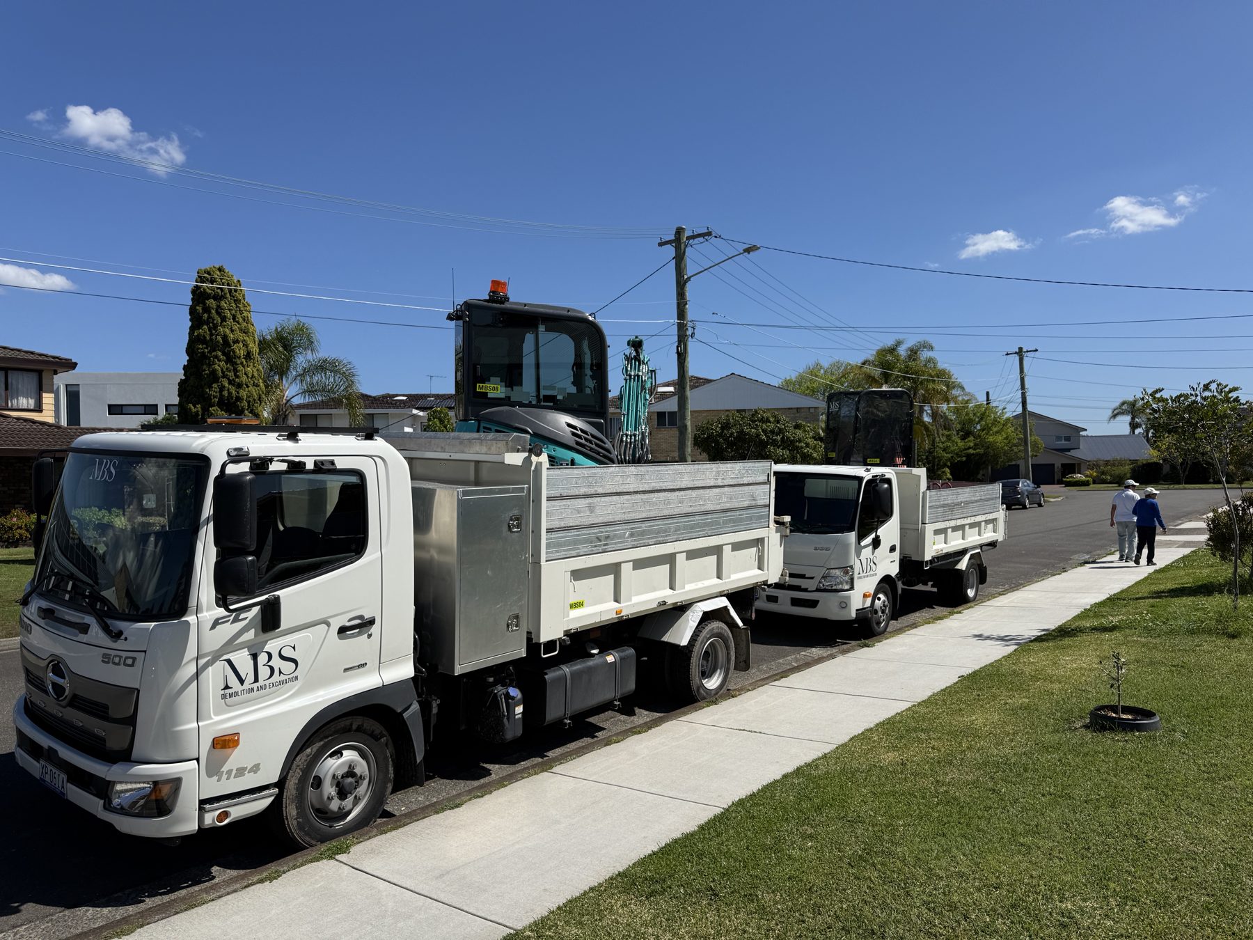 Two MBS Hino tippers loaded with a 3-tonne and 1.7-tonne excavator on a Sydney job